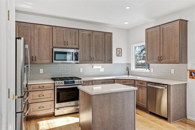 kitchen featuring sink, a center island, stainless steel appliances, light hardwood / wood-style floors, and backsplash