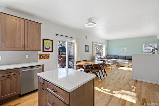 kitchen featuring tasteful backsplash, dishwasher, a kitchen island, and light wood-type flooring