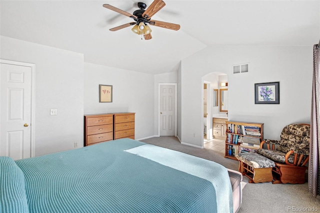 bedroom with light carpet, vaulted ceiling, ceiling fan, and ensuite bathroom