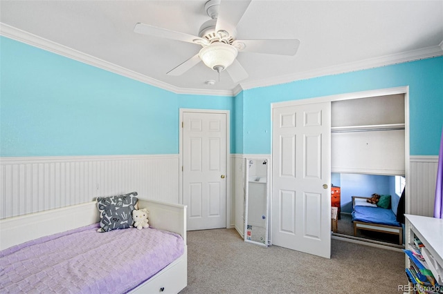 carpeted bedroom featuring crown molding, ceiling fan, and a closet