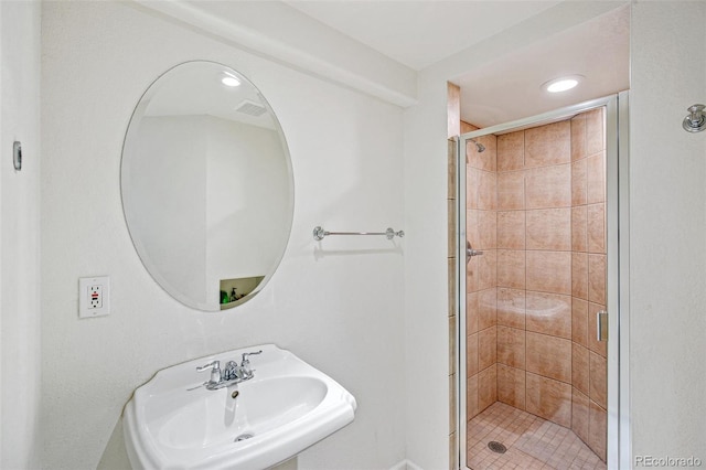 bathroom featuring a shower with door and sink