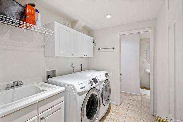 washroom with cabinets, sink, light tile patterned floors, and washing machine and clothes dryer