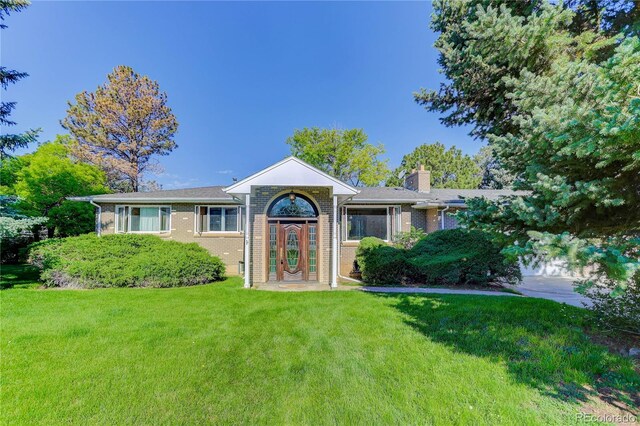 3561 Kalispell St, Aurora, CO 80011 - view of front facade with a front yard, brick siding, and a chimney