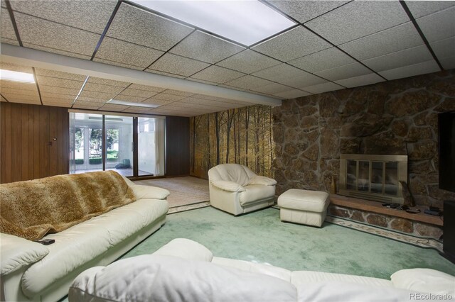 3561 Kalispell St, Aurora, CO 80011 - carpeted living room featuring a paneled ceiling, a stone fireplace, and wood walls