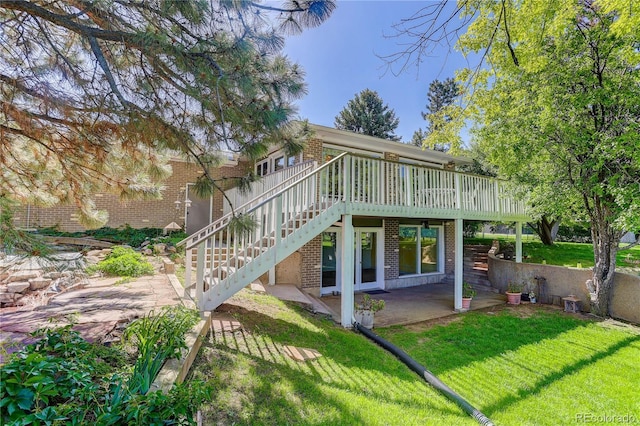 3561 Kalispell St, Aurora, CO 80011 - back of property featuring brick siding, a lawn, a wooden deck, stairway, and a patio area