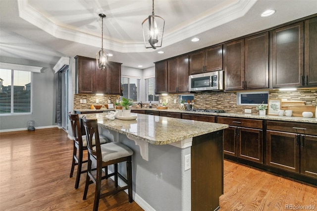 9632 Emerald Vista Dr, Peyton, CO 80831 - kitchen with stainless steel appliances, a raised ceiling, ornamental molding, a breakfast bar area, and a kitchen island