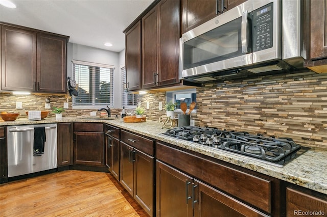 9632 Emerald Vista Dr, Peyton, CO 80831 - kitchen with appliances with stainless steel finishes, tasteful backsplash, light stone counters, dark brown cabinetry, and recessed lighting