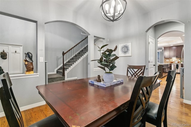 9632 Emerald Vista Dr, Peyton, CO 80831 - dining room featuring arched walkways, light wood finished floors, stairway, and a chandelier