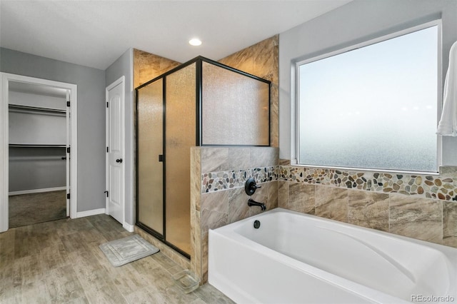 9632 Emerald Vista Dr, Peyton, CO 80831 - bathroom featuring a stall shower, a garden tub, wood finished floors, and a spacious closet