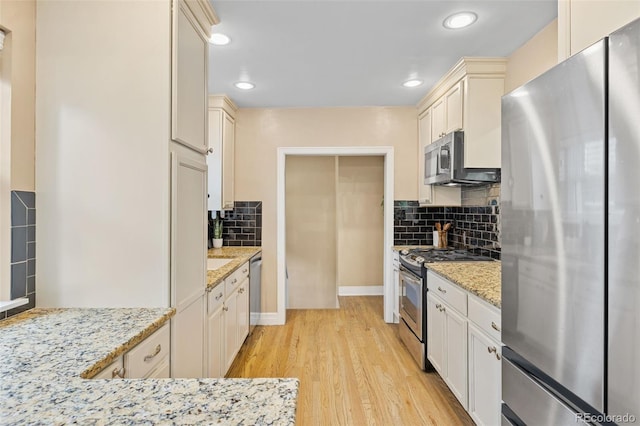 3334 W 37th Ave, Denver, CO 80211 - kitchen featuring appliances with stainless steel finishes, backsplash, light wood finished floors, recessed lighting, and light stone counters