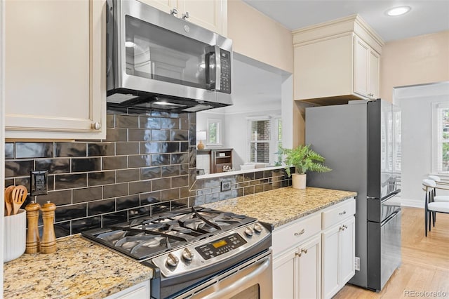 3334 W 37th Ave, Denver, CO 80211 - kitchen with appliances with stainless steel finishes, decorative backsplash, light stone counters, recessed lighting, and white cabinetry