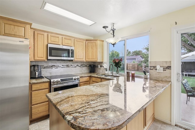 7075 Welch Ct, Arvada, CO 80004 - kitchen with appliances with stainless steel finishes, a sink, light brown cabinetry, and a peninsula