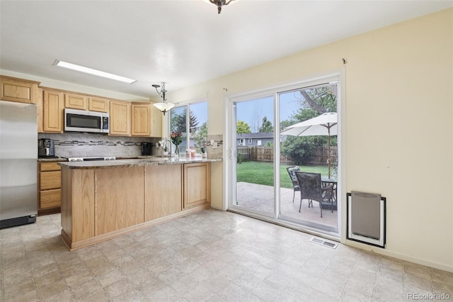 7075 Welch Ct, Arvada, CO 80004 - kitchen featuring appliances with stainless steel finishes, healthy amount of natural light, a peninsula, and light brown cabinets