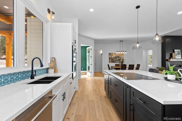 kitchen featuring hanging light fixtures, light stone countertops, sink, and stainless steel appliances