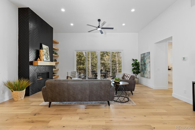 living room with light hardwood / wood-style flooring, a fireplace, and ceiling fan