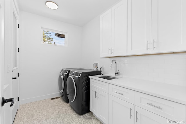 clothes washing area featuring washer and dryer, sink, and cabinets