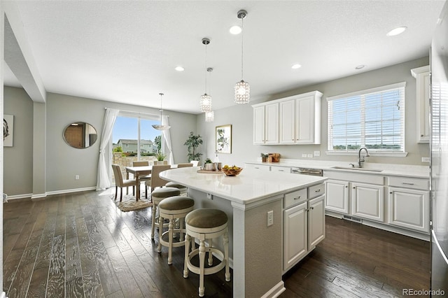 12554 Hudson Ct, Thornton, CO 80241 - kitchen with a center island, light countertops, dark wood-type flooring, white cabinets, and recessed lighting