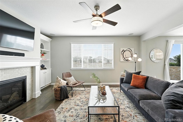 12554 Hudson Ct, Thornton, CO 80241 - living area with dark wood-style floors, a ceiling fan, and a fireplace