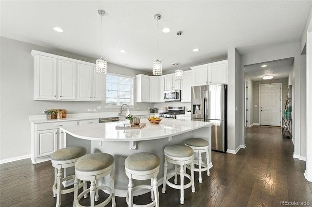 12554 Hudson Ct, Thornton, CO 80241 - kitchen featuring appliances with stainless steel finishes, dark wood-style flooring, a center island, white cabinetry, and recessed lighting