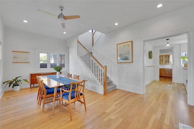 dining area featuring a ceiling fan, light wood-style flooring, a wealth of natural light, and stairway