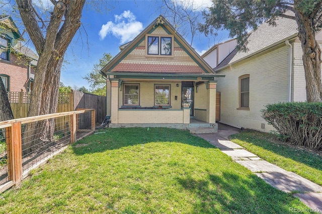 view of front of house with fence, covered porch, a front lawn, and brick siding