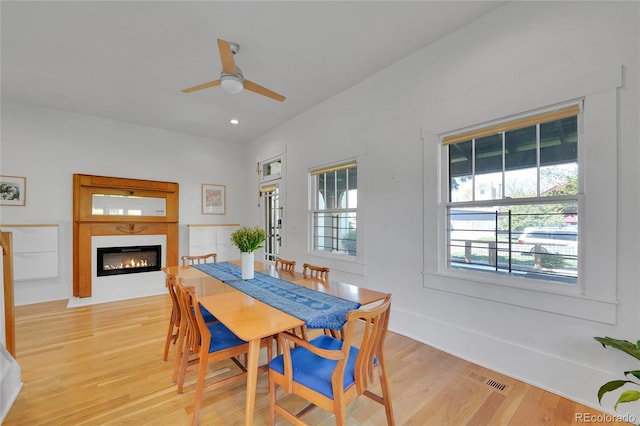 dining area with visible vents, a glass covered fireplace, light wood-style floors, recessed lighting, and a ceiling fan
