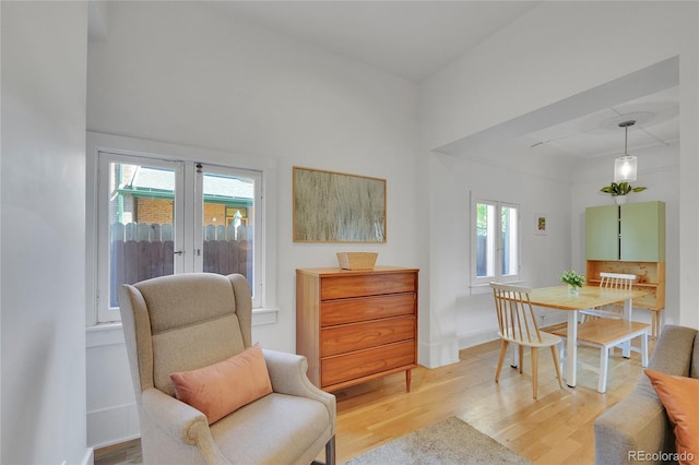 sitting room with baseboards, a tray ceiling, and light wood-style flooring
