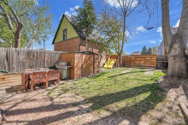 view of yard featuring a storage shed, an outbuilding, a fenced backyard, and a patio area