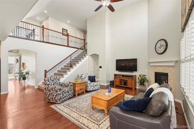 living area featuring baseboards, stairway, a high ceiling, and a ceiling fan