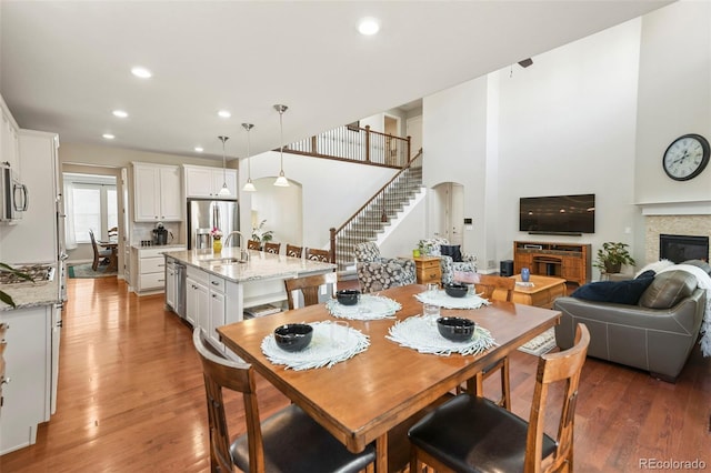 dining room featuring a glass covered fireplace, recessed lighting, stairway, and wood finished floors