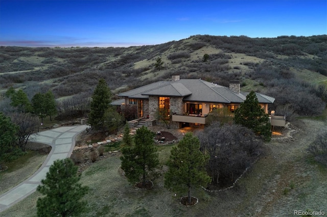 view of front of house with stone siding, a chimney, and a mountain view