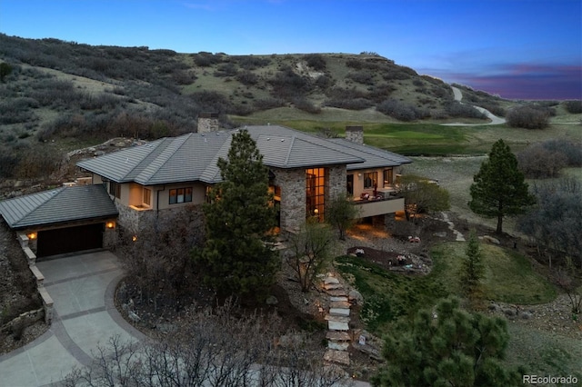 exterior space featuring stone siding, a chimney, and concrete driveway