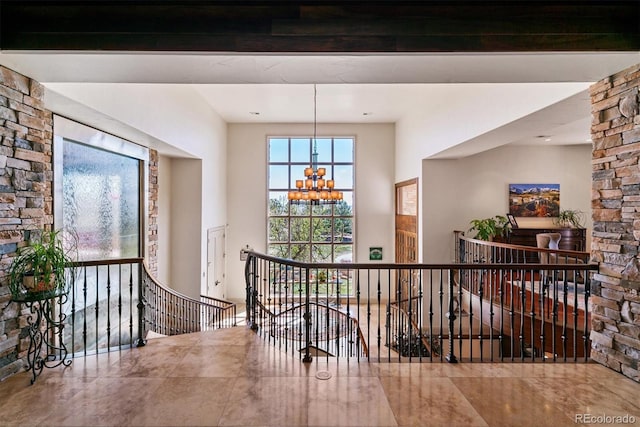 hall with an inviting chandelier, an upstairs landing, and beamed ceiling