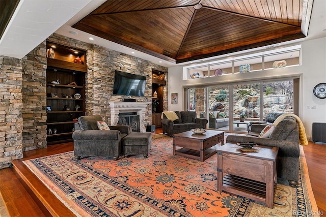 living area featuring wooden ceiling, a large fireplace, wood finished floors, and a tray ceiling