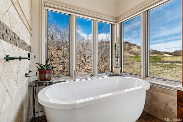 bathroom featuring tile walls and a soaking tub