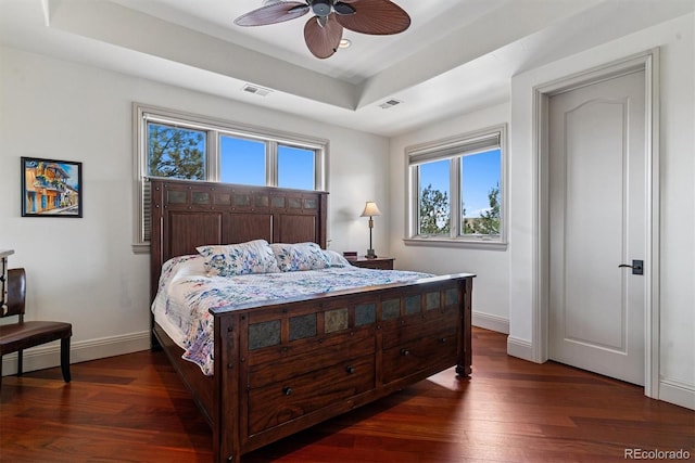 bedroom with baseboards, wood finished floors, visible vents, and a raised ceiling