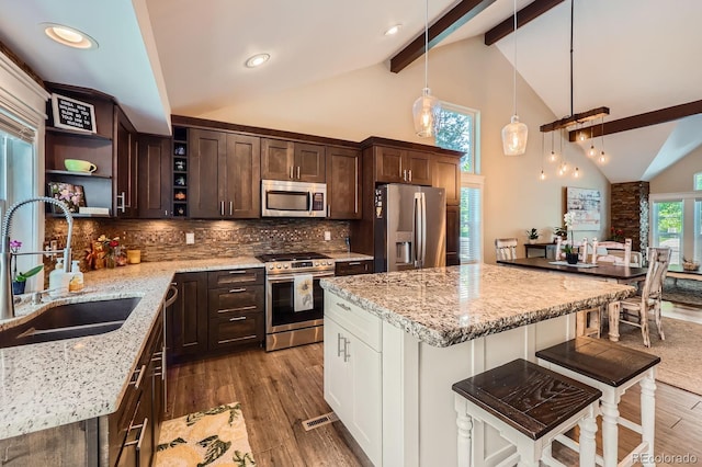 7445 Shoreham Pl, Castle Pines, CO 80108 - kitchen with appliances with stainless steel finishes, open shelves, dark brown cabinetry, light stone countertops, and light wood-style floors