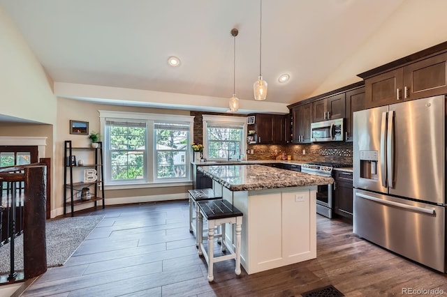 7445 Shoreham Pl, Castle Pines, CO 80108 - kitchen featuring appliances with stainless steel finishes, dark brown cabinets, dark stone counters, dark wood finished floors, and a kitchen island
