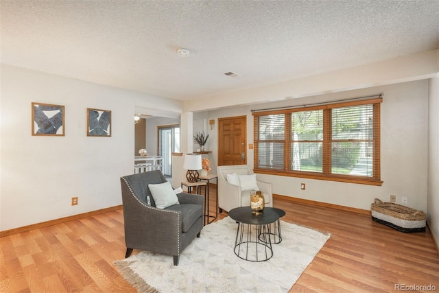 living room with light wood finished floors, baseboards, and a textured ceiling