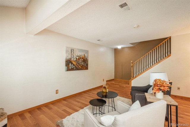 living area featuring wood finished floors, stairway, and baseboards