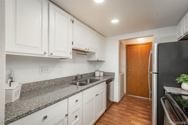kitchen with stainless steel appliances, a sink, light wood-style floors, white cabinetry, and recessed lighting