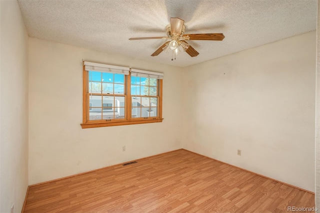 spare room featuring light wood-style floors, ceiling fan, and a textured ceiling