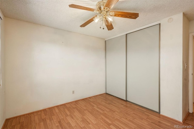 unfurnished bedroom featuring light wood-style floors, a closet, a textured ceiling, and a ceiling fan