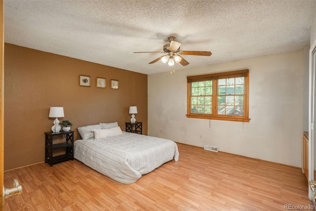 bedroom featuring light wood finished floors, a textured ceiling, and ceiling fan