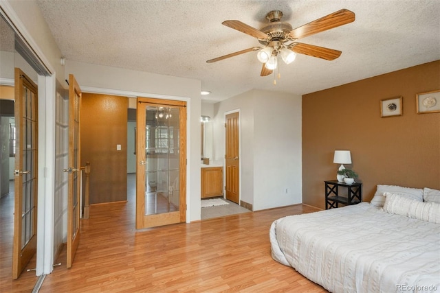 bedroom with light wood-style flooring, a textured ceiling, french doors, baseboards, and a ceiling fan