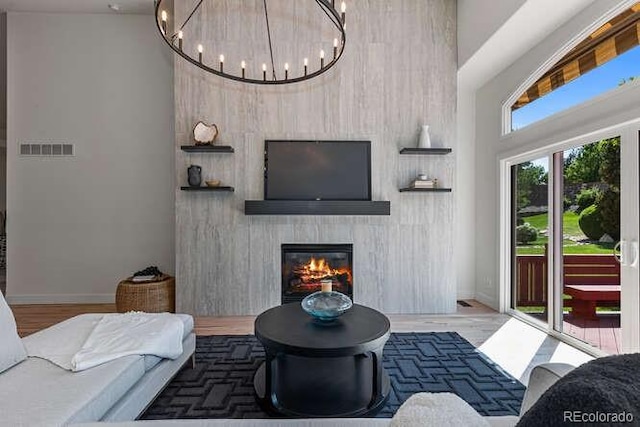 9561 Silver Hill Cir, Lone Tree, CO 80124 - living room with a towering ceiling, a glass covered fireplace, a chandelier, and wood finished floors