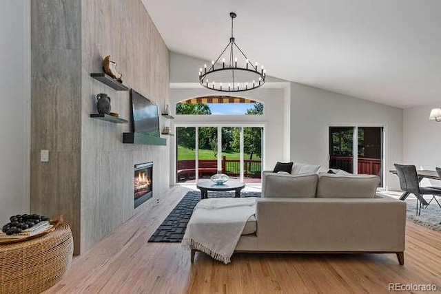9561 Silver Hill Cir, Lone Tree, CO 80124 - living room with a chandelier, lofted ceiling, light wood-type flooring, and a glass covered fireplace