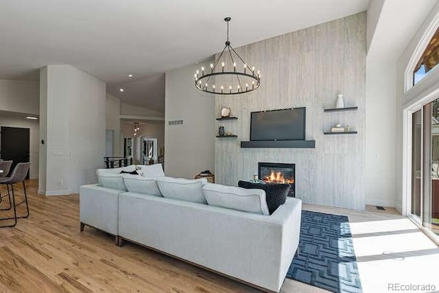 9561 Silver Hill Cir, Lone Tree, CO 80124 - living room featuring a chandelier, a glass covered fireplace, light wood-style floors, and high vaulted ceiling