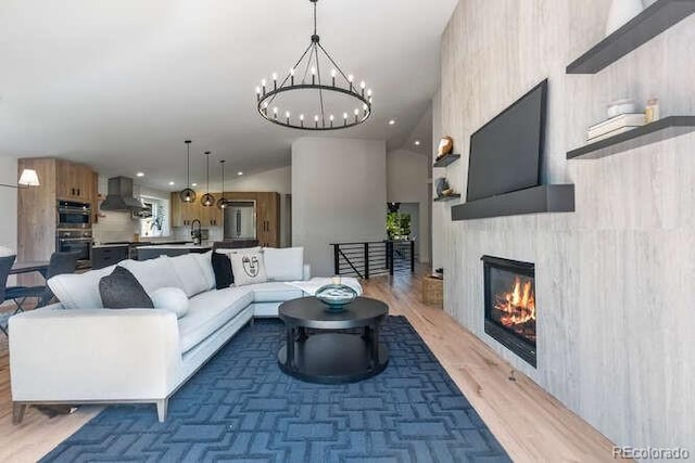 9561 Silver Hill Cir, Lone Tree, CO 80124 - living room with wood finished floors, a chandelier, a glass covered fireplace, and recessed lighting