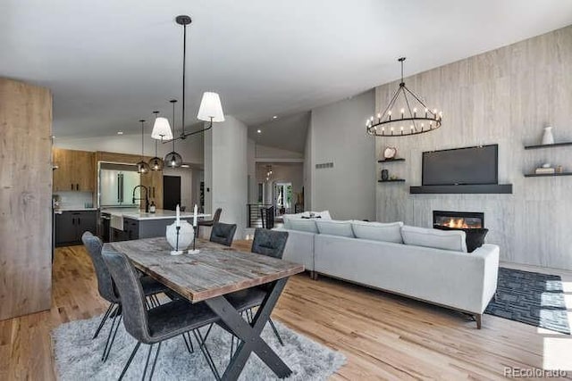 9561 Silver Hill Cir, Lone Tree, CO 80124 - dining area featuring a chandelier, a glass covered fireplace, light wood-type flooring, and lofted ceiling